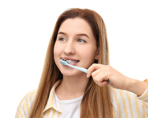 Smiling woman with dental braces cleaning teeth on white background