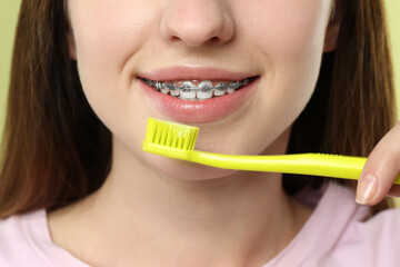 Smiling woman with dental braces cleaning teeth, closeup