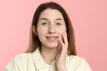 Portrait of smiling woman with dental braces on pink background