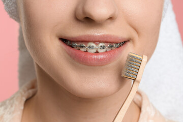 Smiling woman with dental braces and toothbrush, closeup