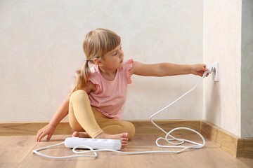 Little child playing with electrical socket and power strip plug at home. Dangerous situation