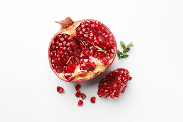 Cut fresh pomegranate and green leaves on white background, flat lay