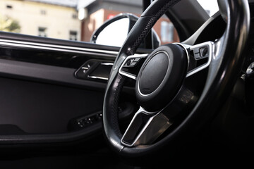 Steering wheel inside modern black car, closeup view