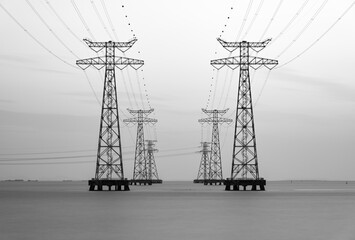 High voltage transmission towers over sea water, long exposure
