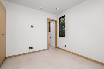 a small room with a big door and window and all white walls