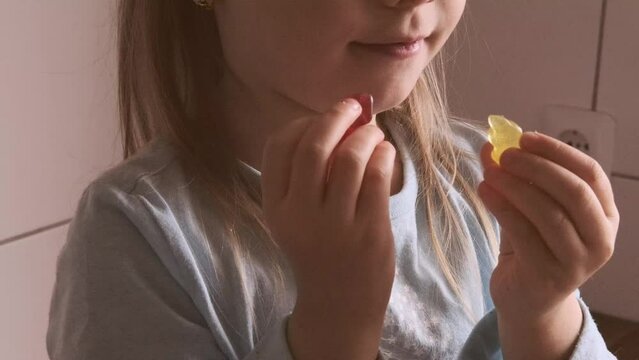 cute small child, blonde girl 5 years old enjoys tasty gelatinous gummy sweets, kid has good appetite, happy childhood, balanced diet, sweet life, unhealthy food, halal food