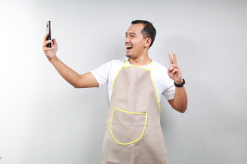 Asian man barista bartender barman employee in brown apron white t-shirt work coffee shop do selfie...