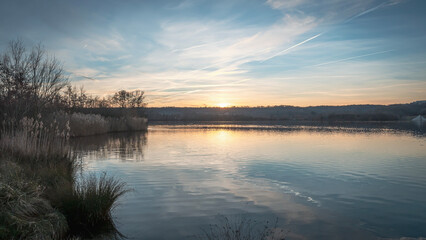 an empty lake sits under a blue and orange sky during the sun