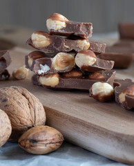nuts and chocolate pieces on a wooden board with one bite taken out