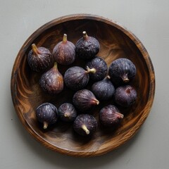 Fototapeta premium A round wooden plate holding several dark purple figs