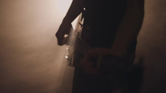 Man playing electric guitar on haze filled stage