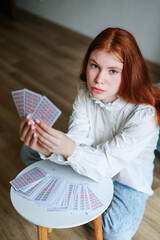 girl with red hair serious hold tarot cards