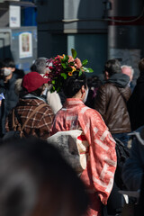 A girl in a bright kimono and flowers in a high hairstyle walks in a crowd of people in Tokyo near the Shibuya intersection