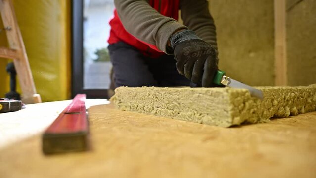 Worker Cutting Piece of Mineral Wool Insulation