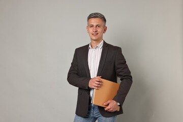 Happy teacher with notebooks on grey background