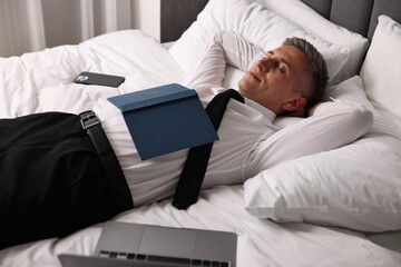 Businessman in office clothes sleeping on bed indoors