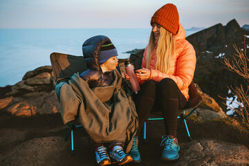 Family picnic in mountains - mother and child drinking tea from thermos sitting in camping chairs travel lifestyle vacations outdoor woman with kid hiking together adventure trip