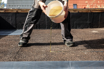 man applies adhesive to an old bitumen sealant and then glues on a rubber sheet
