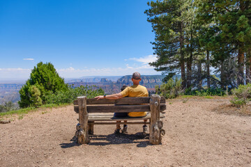 Father and son sitting on a wooden bench, enjoying a scenic view of the Grand Canyon
