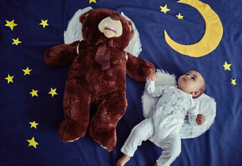 Above, baby and lying in bed with teddy bear as gift or present or toy for fun at home. Kid,...