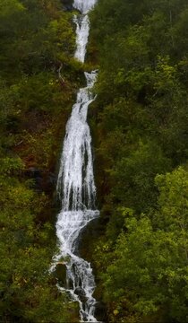 Drone vertical slow-motion of natural waterfall in a hidden forest in Trysil, Norway