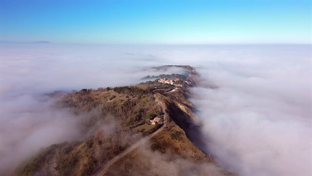 Aerial view of Fiorenzuola di Focara village covered with dense fog at sunrise, Italy