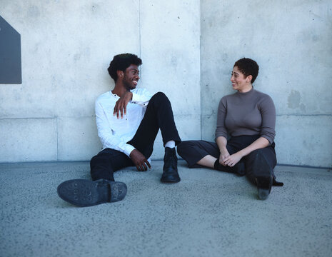 Man and woman sitting against a concrete wall having a conversation