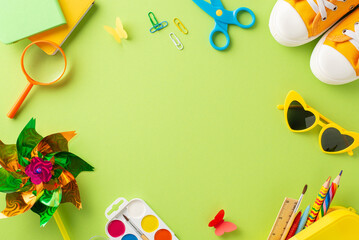 Outdoor education setup for young learners. Top view of creative tools - crayon case, paint set, magnifier, heart shaped shades, shoes, pinwheel and more on pastel green. Space for text or promotion