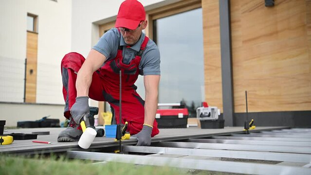 Man in Red Overalls and Hat Working on a Patio Deck