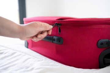 Hand of a young man closing his red suitcase.