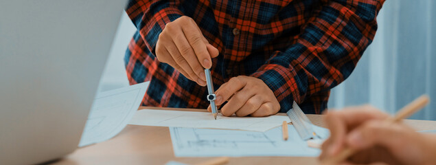A professional engineer uses divider to measure blueprint during skilled architect drawing...