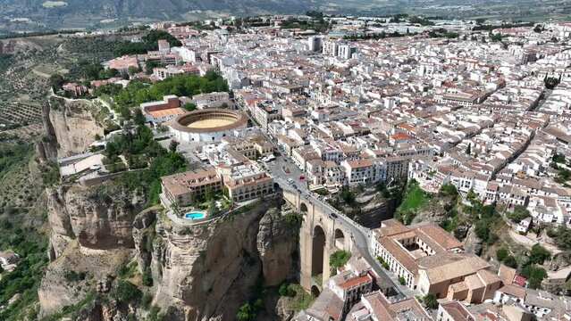 Cinematic aerial video of historic houses built on the edge of the cliff with bridge and waterfall in Ronda, Spain