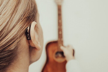 A woman with a hearing aid plays the guitar. I can hear music again! Technologies to assist people...