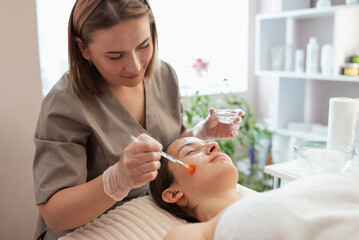 Female client getting cold hydrating procedure in beauty salon. Professional cosmetologist applying...