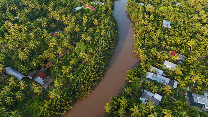 Beautiful aerial view of Mekong Delta countryside, coconut land with vast coconut, nipa palm jungle, riverside house and waterway transport good for Vietnam ecotourism at Ben Tre