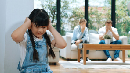 Stressed and unhappy young girl huddle in corner, cover her ears blocking sound of her parent...