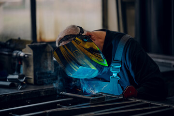 Man worker working with a metal product and welding it with a arc welding machine in a workshop....