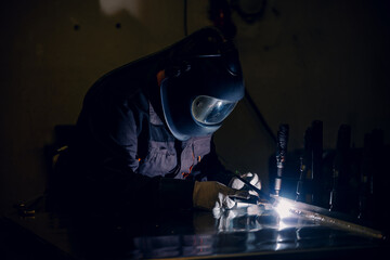 Man worker working with a metal product and welding it with a arc welding machine in a workshop....