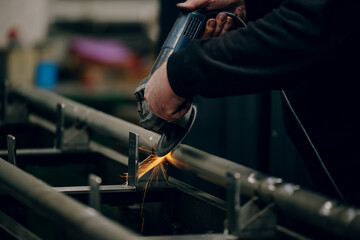Hands of worker grinding a piece of metal