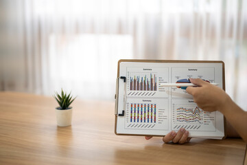 A person is pointing at a graph on a clipboard