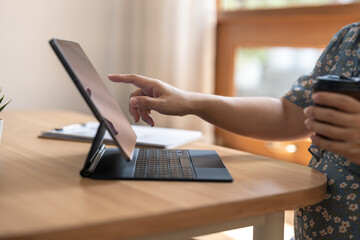 A woman is using a tablet with her finger pointing at something on the screen