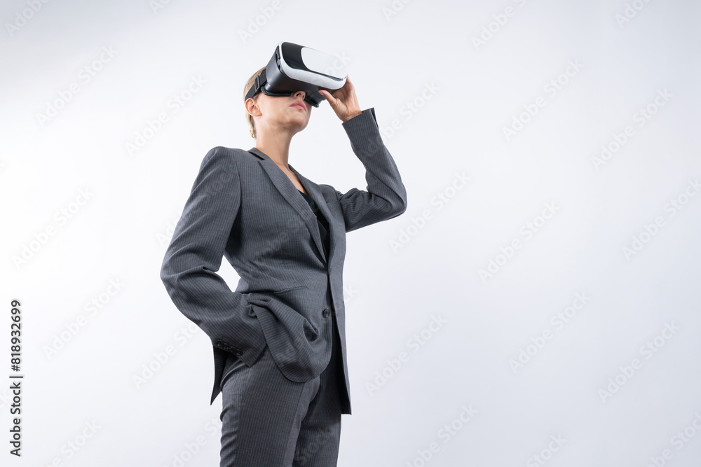 Wall mural Skilled businesswoman looking at visual reality world by using VR glass while standing at background. Smart manager holding VR goggle to connect metaverse by using technology innovation. Contraption.