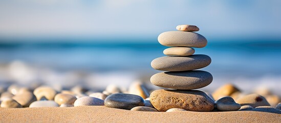A zen symbol in the form of a pyramid of stones resting on sandy ground representing harmony and balance The image also includes the serene backdrop of the ocean with a closeup of a tower of sea pebb