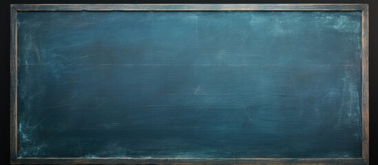 A dark blue chalkboard with traces of erasing featuring a full surface frame and a textured background Copy space image