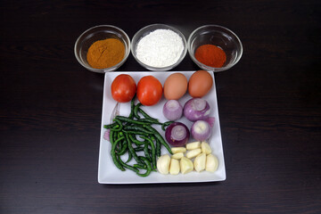 Eggs, tomatoes, green chilies, garlic, onions, spices, chives, chili powder and corn flour are arranged on the table