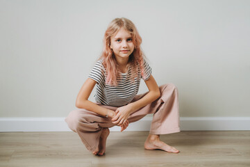 A 9-year-old girl fashionably poses against the wall.