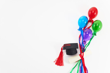 Graduation Celebration Concept. Top view of graduation cap, diploma, and colorful balloons on white.