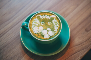 Delicious green matcha latte tea with foam on a wooden table.