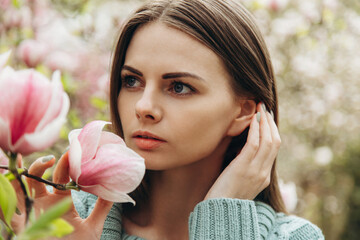 Spring portrait of young woman near blooming magnolia.