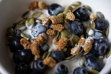 CLOSE UP COOKED PORRIDGE WITH HEALTHY FRUIT TOPPINGS , VEGAN OAT CREAM